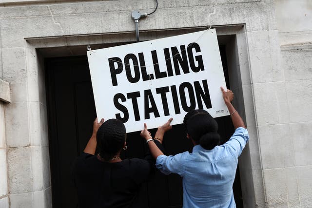 Workers prepare signs outside their polling station on general election day in London