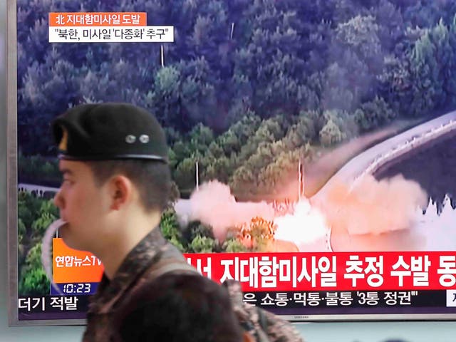 A South Korean soldier walks past a TV broadcast of a news report on North Korea firing what appeared to be several land-to-ship missiles off its east coast at a railway station in Seoul