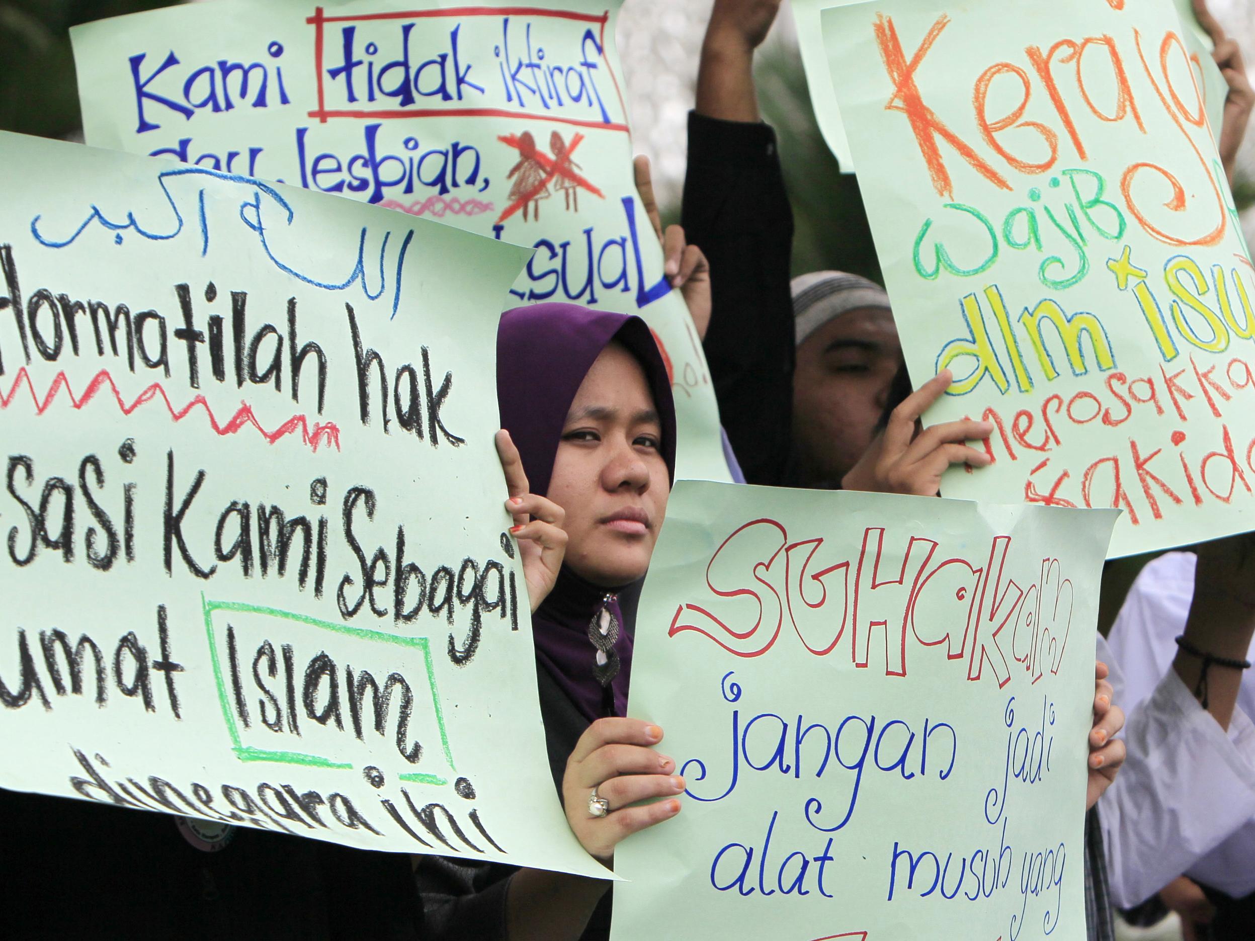 Malaysian Muslims hold placards protesting against gay rights in Kuala Lumpur in country where sexual identity remains a divisive issue