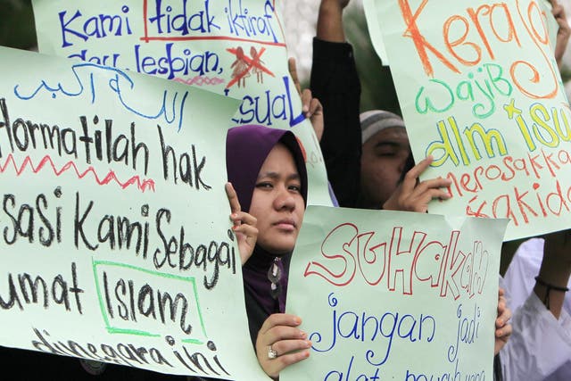 Malaysian Muslims hold placards protesting against gay rights in Kuala Lumpur in country where sexual identity remains a divisive issue