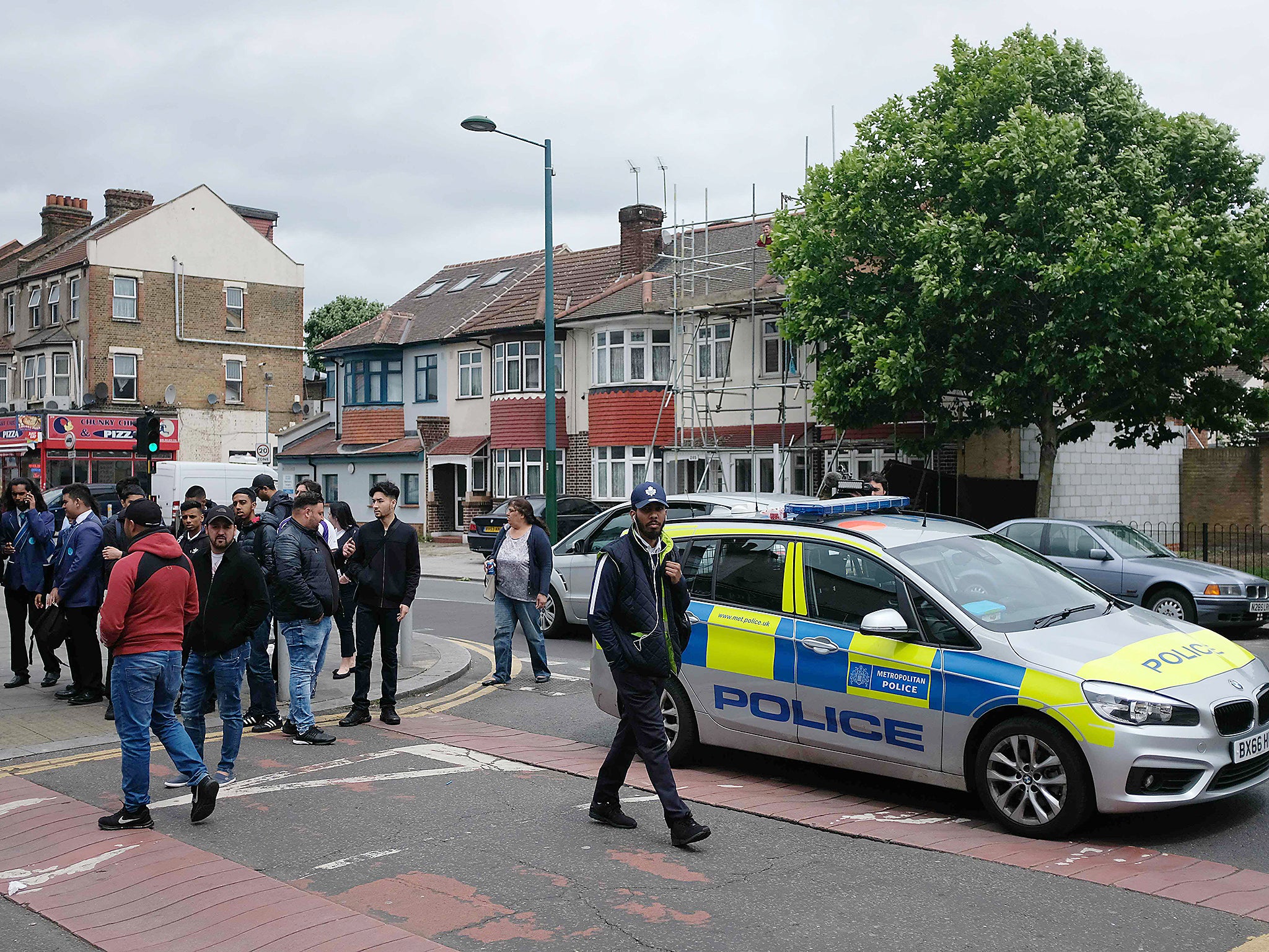 People gather by a Police cordon, near to the Ummah Fitness Centre, in Ilford, east of London, following a raid on the gym, as police continue their investigations into June 3 terror attack