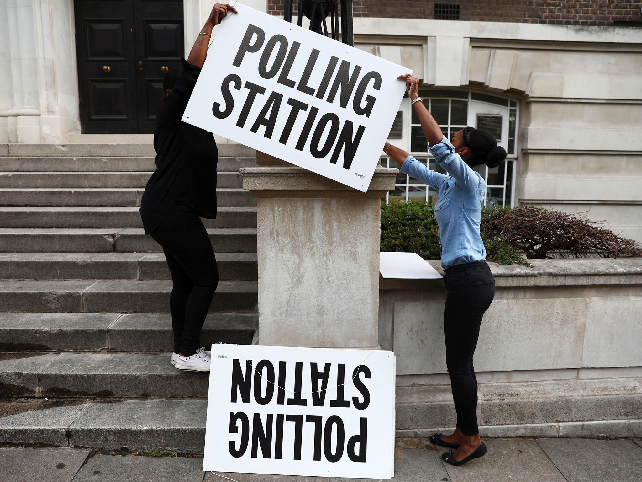 Workers prepare signs outside their polling station on general election day in London on 8 June 2017