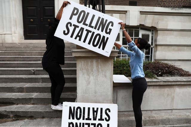 Workers prepare signs outside their polling station on general election day in London on 8 June 2017