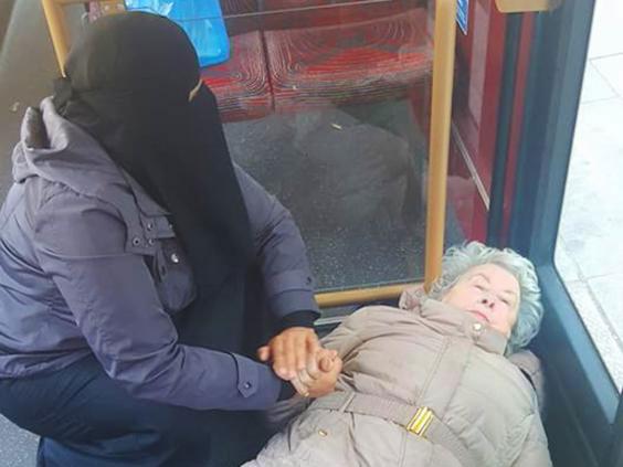 A Muslim woman (pictured left) holding hands with an elderly lady who fell over in the bus