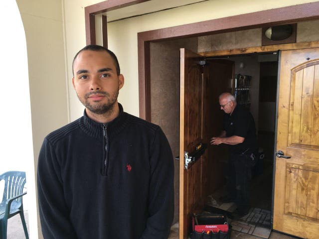 Drew Williams, a member of the Eugene Islamic Center, poses for a portrait outside the building in Eugene, Oregon, as locksmith Jim King upgrades the locks on the front doors. 