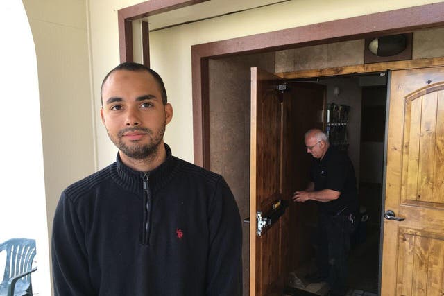 Drew Williams, a member of the Eugene Islamic Center, poses for a portrait outside the building in Eugene, Oregon, as locksmith Jim King upgrades the locks on the front doors. 