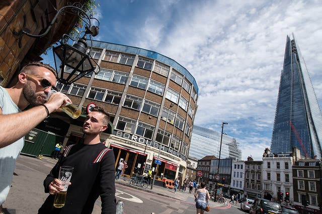 Two men drink beer outside the Southwark Tavern which reopened for business today next to an entrance to Borough Market which remains closed in London
