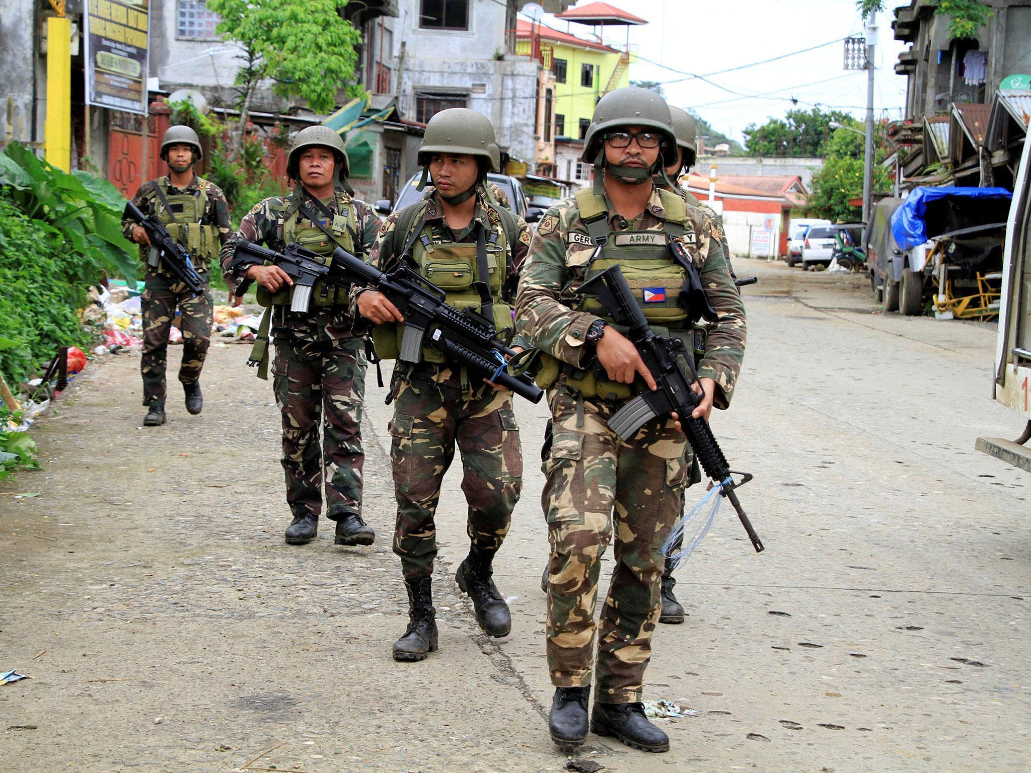 A joint group of police and military forces on foot patrol conduct a house to house search as part of clearing operations in different sections of Marawi city, Philippines