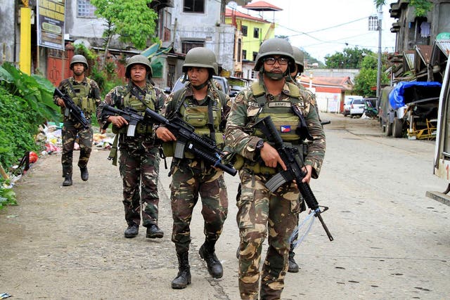 A joint group of police and military forces on foot patrol conduct a house to house search as part of clearing operations in different sections of Marawi city, Philippines
