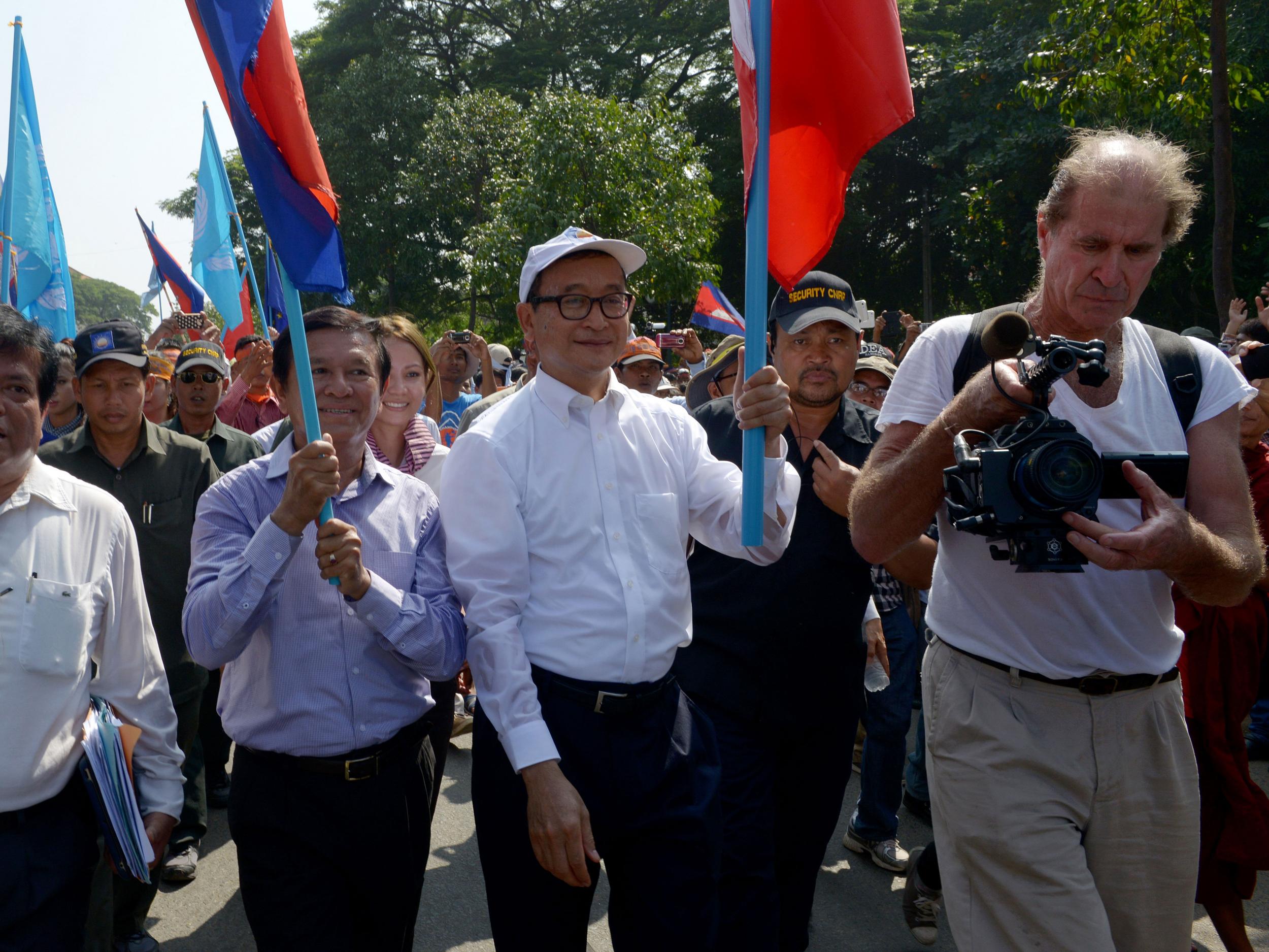 Australian James Ricketson (R) filming as Sam Rainsy (Center-R), former opposition leader, and Kem Sokha (Center-L) opposition leader attend a demonstration in Phnom Penh