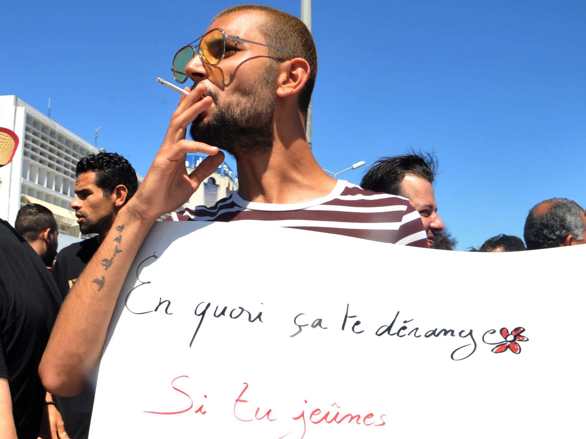 A Tunisian protester smoked a cigarette and held a placard reading "Why is it bothering you?"
