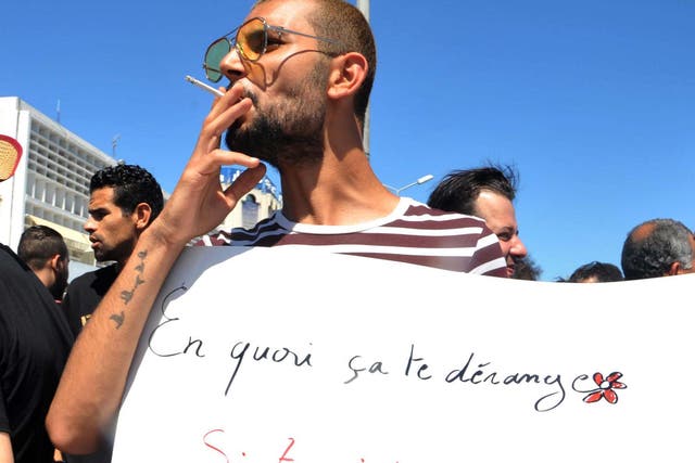A Tunisian protester smoked a cigarette and held a placard reading "Why is it bothering you?"