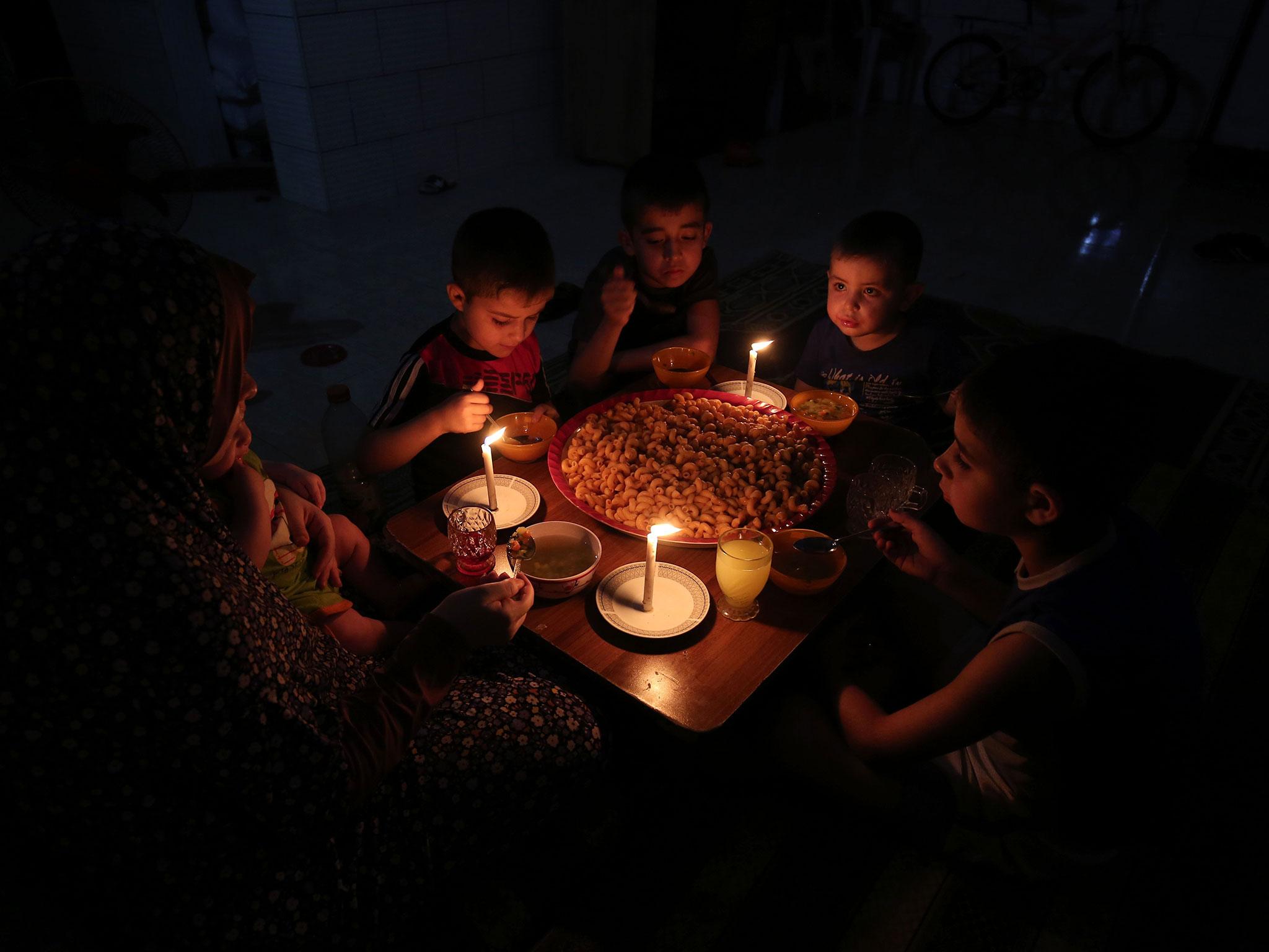 A Palestinian family eats dinner during a power cut on Sunday at their makeshift home at the Rafah refugee camp in the southern Gaza Strip