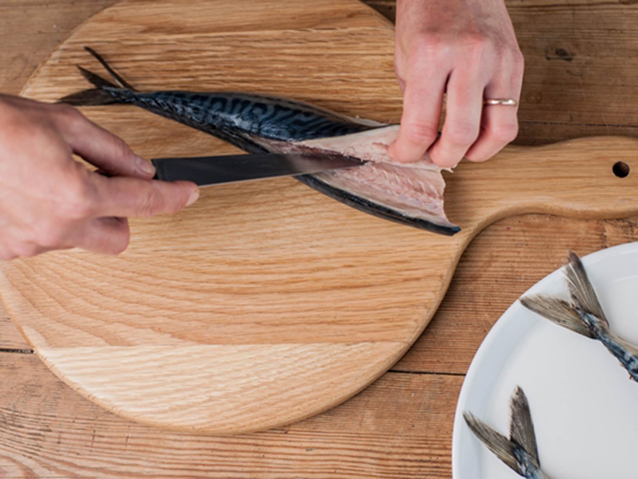 Using sweeping motions, cut the fillet away, keeping as close to the backbone as possible and holding the knife parallel to the board