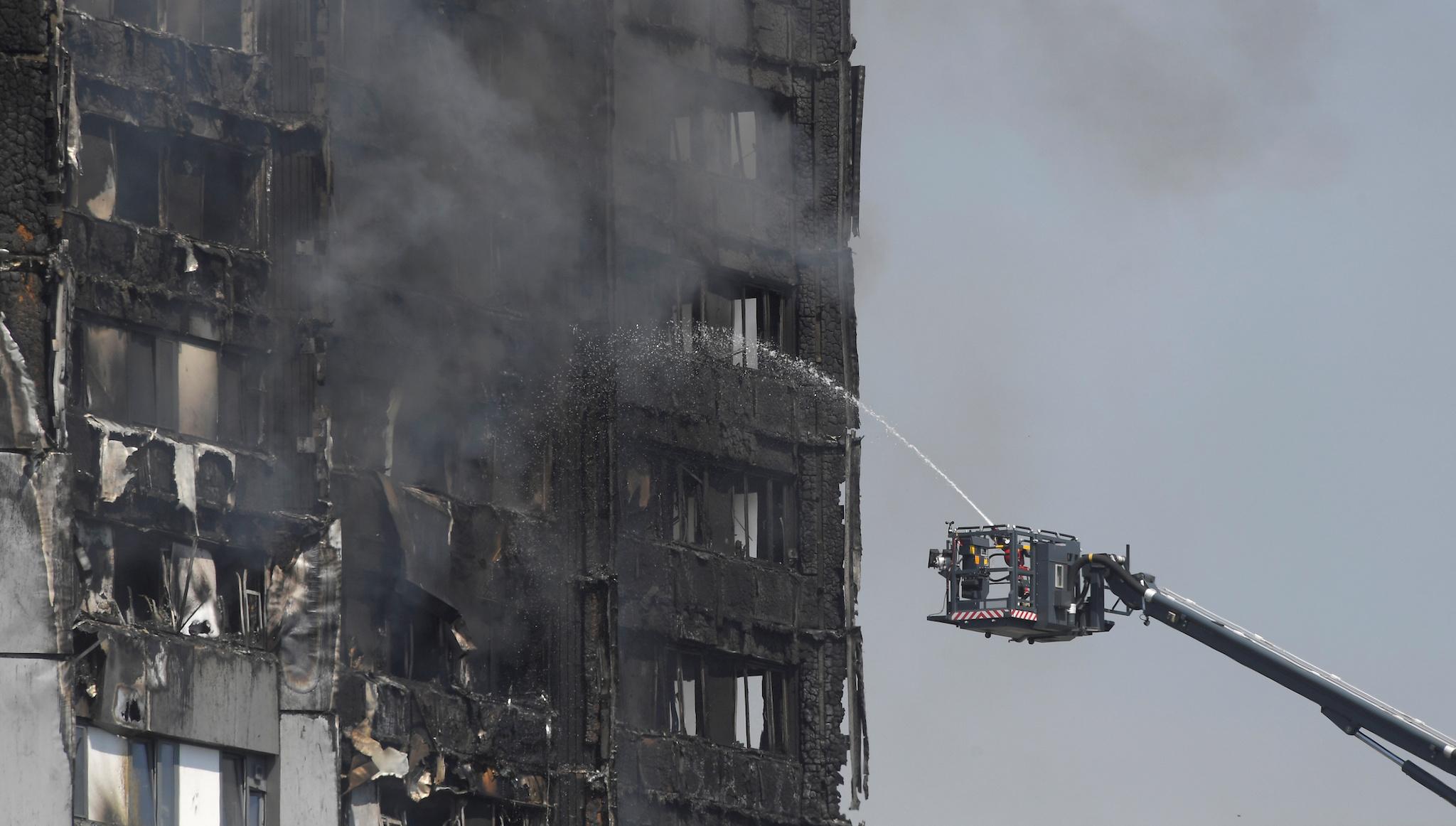Firefighters direct jets of water onto a tower block