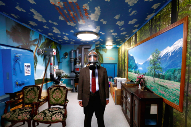 Seiichiro Nishimoto, CEO of Shelter Co., poses wearing a gas mask at a model room for the company's nuclear shelters in the basement of his house in Osaka, Japan.