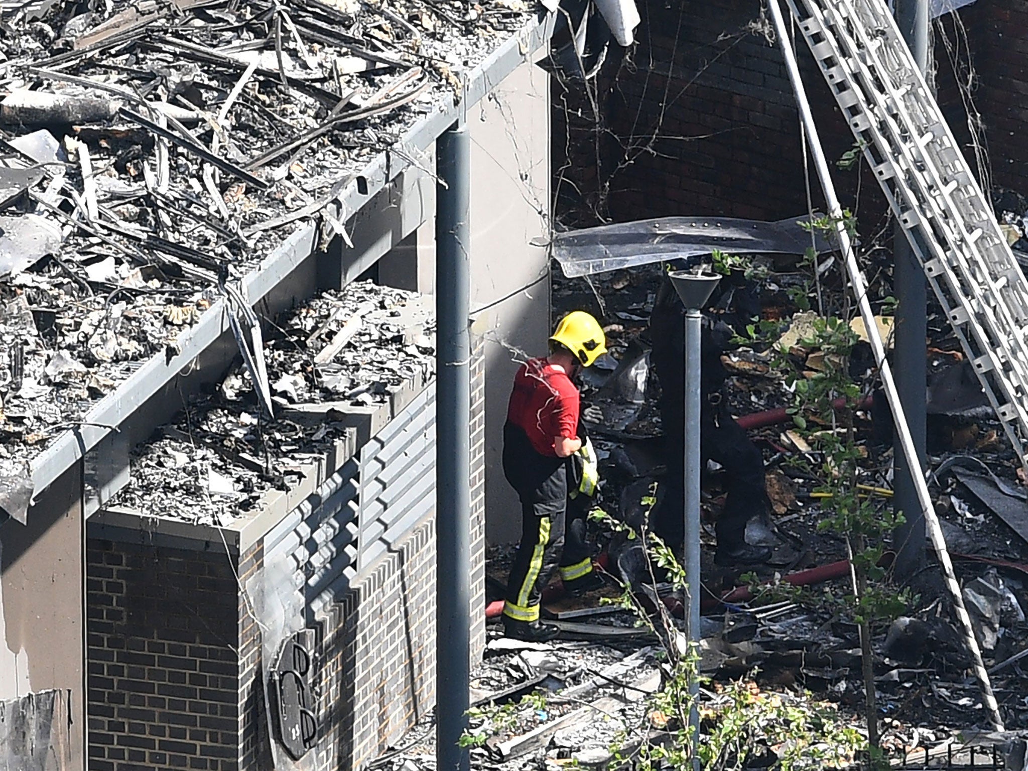A firefighter is seen among the rubble in the aftermath of a fire at Grenfell Tower