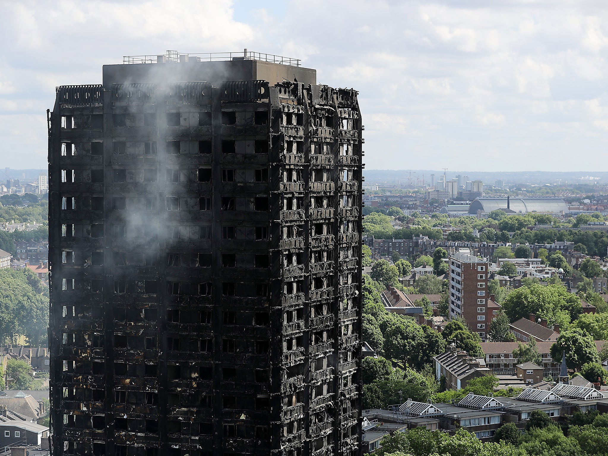 Debris hangs from the blackened exterior of Grenfell Tower