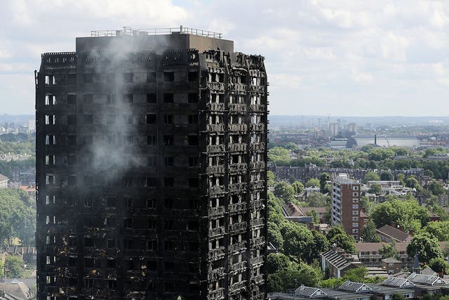 Debris hangs from the blackened exterior of Grenfell Tower