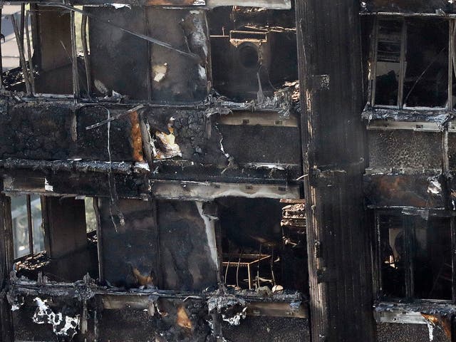 Remains of furniture are seen through the windows as smoke still emerges from the charred Grenfell Tower