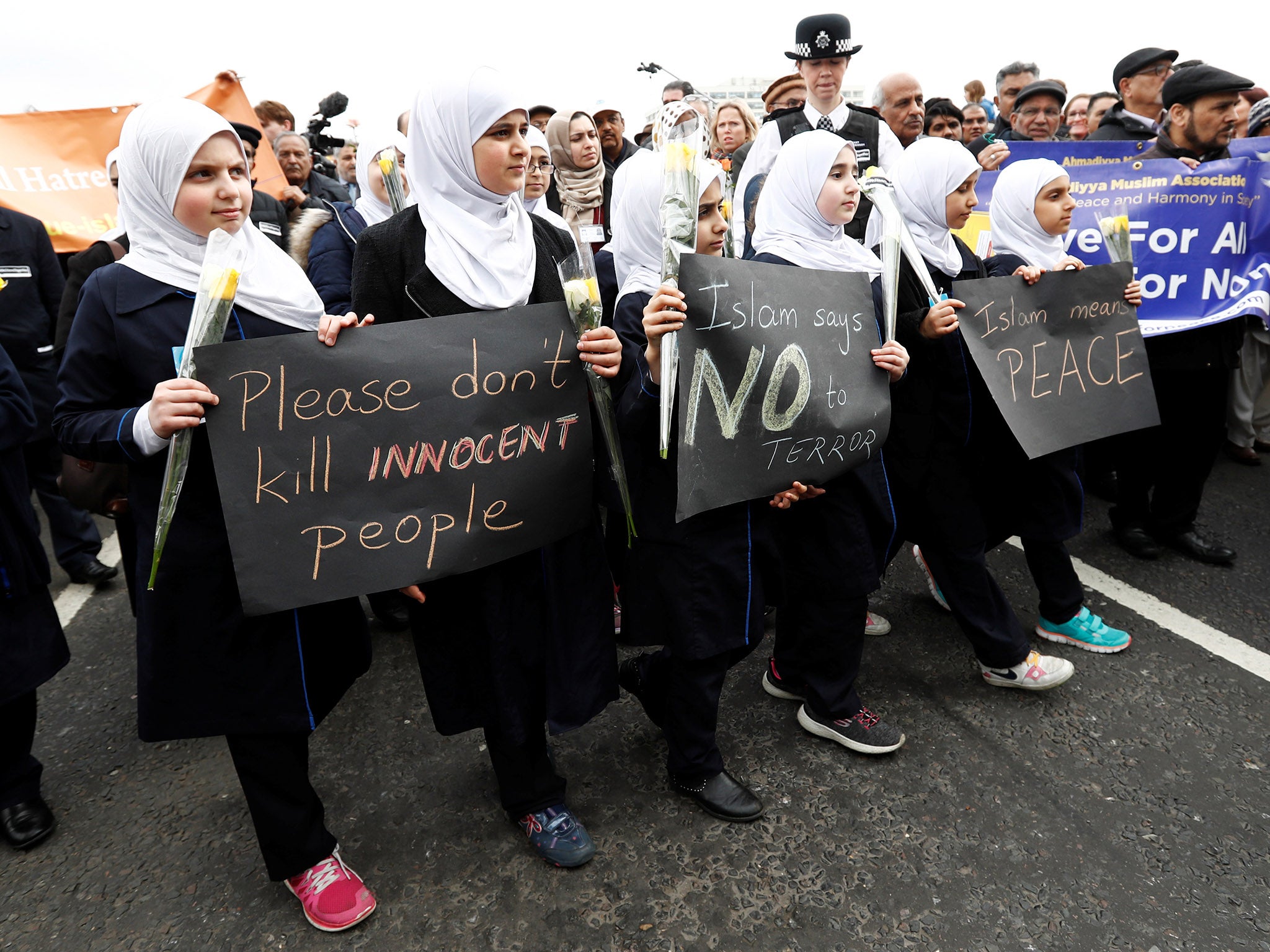 ‘Islam means peace,’ one sign reads as Muslim girls join a crowd paying tribute to those killed in the attack on Westminster Bridge in London