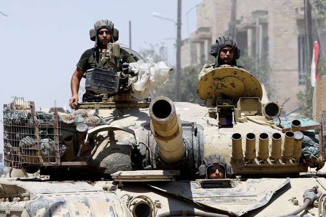 Iraqi soldiers look out from a tank as they advances towards the Isis positions