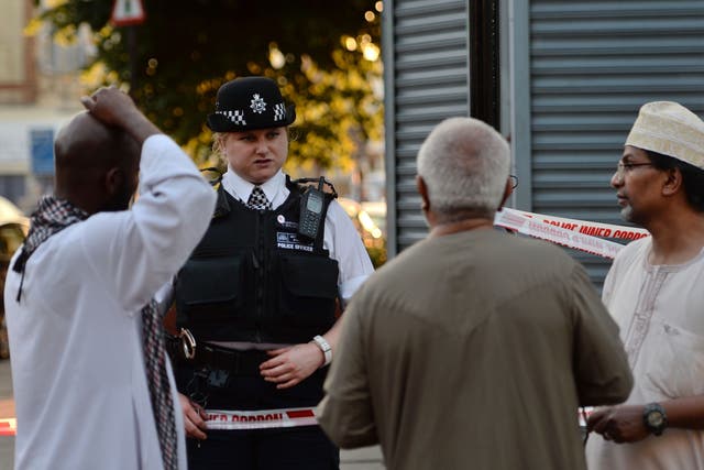 A police officer talks to local people at Finsbury Park in north London, where one man has died