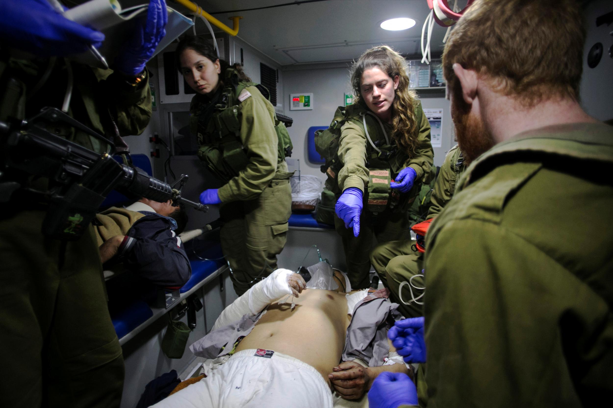 Israeli soldiers give initial medical treatment to wounded Syrians in the Israeli-occupied Golan Heights on 18 January 2017