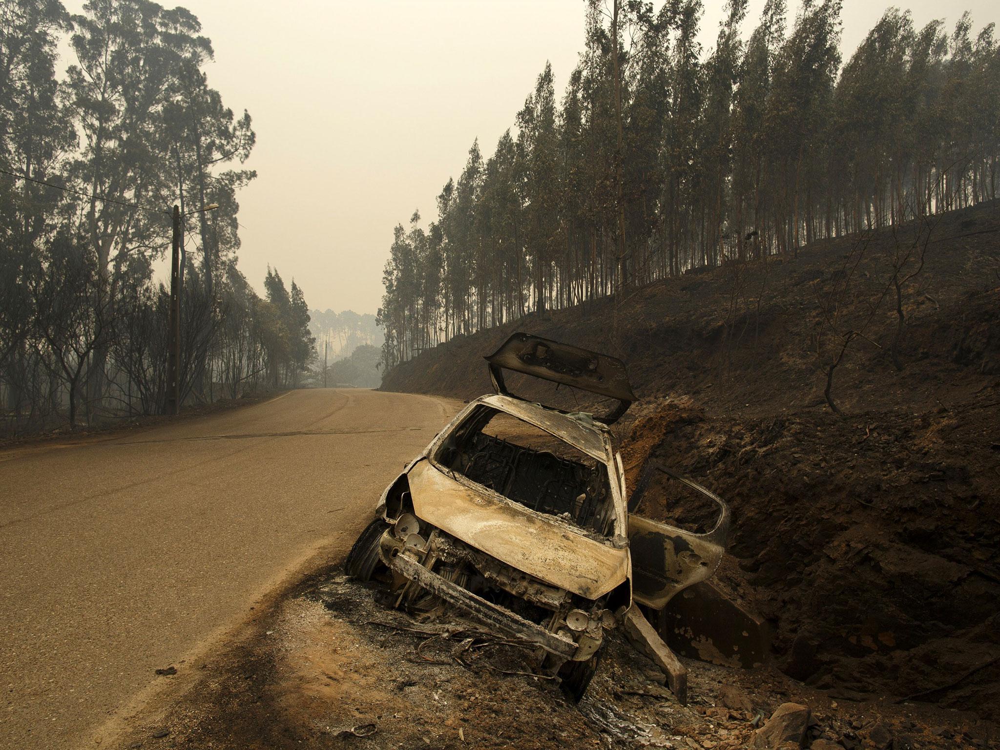 A burnt-out car stands on the side of the road after a wildfire took dozens of lives near Castanheira de Pera, in Leiria district, Portugal