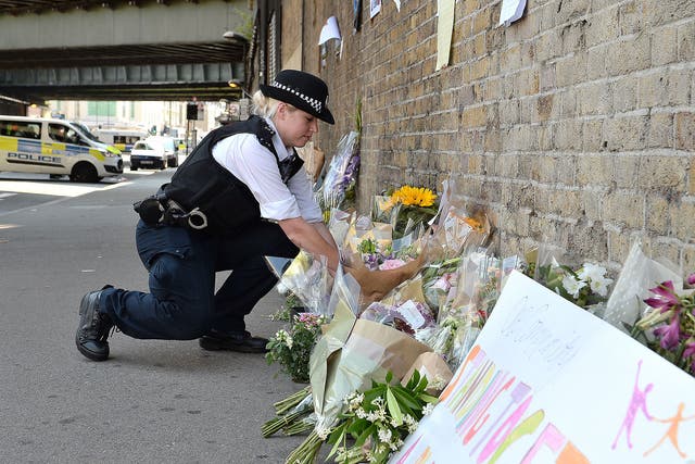 A police officer lays flowers passed over by a member of the public, close to Finsbury Park Mosque in north London