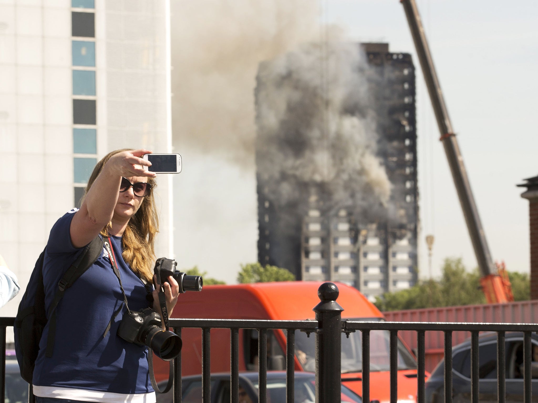 Bystanders are said to be taking photos in front of the blackened skeleton of the tower block without paying their respects