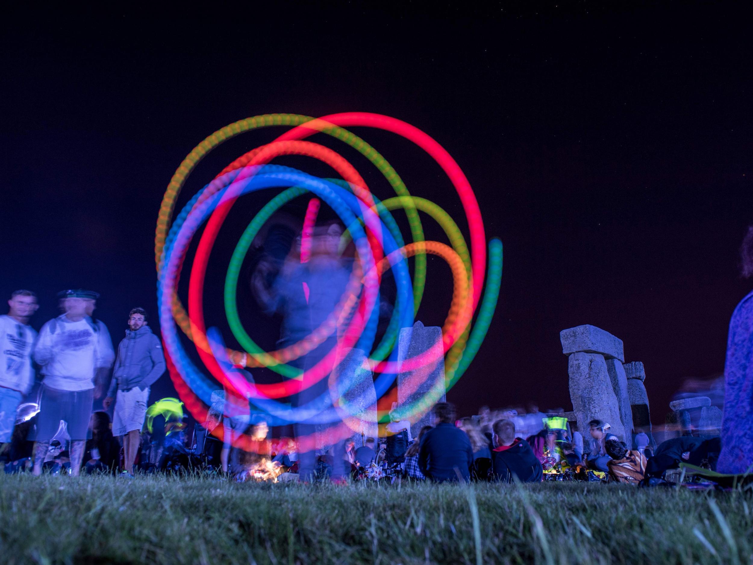 A reveller spins glow sticks as people gather to celebrate the pagan festival of Summer Solstice at Stonehenge