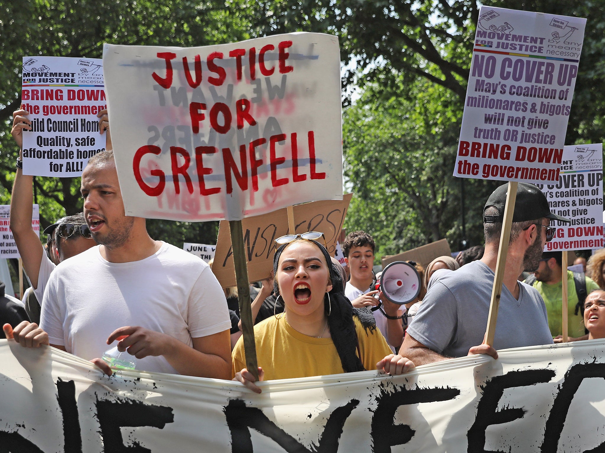 Protesters hold signs calling for justice for the victims of the Grenfell Disaster