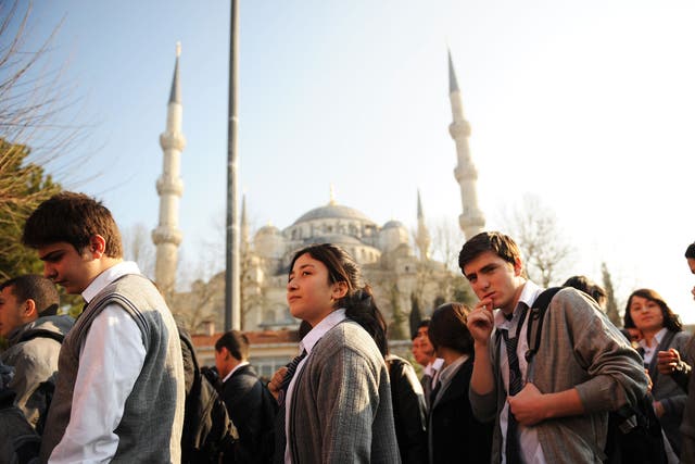 Turkish students listen to their teacher before entering their high school early in the morning in Istanbul on March 23, 2012.
