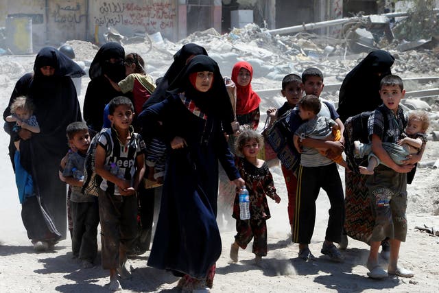 Displaced women and children who fled from clashes walk in the Old City of Mosul