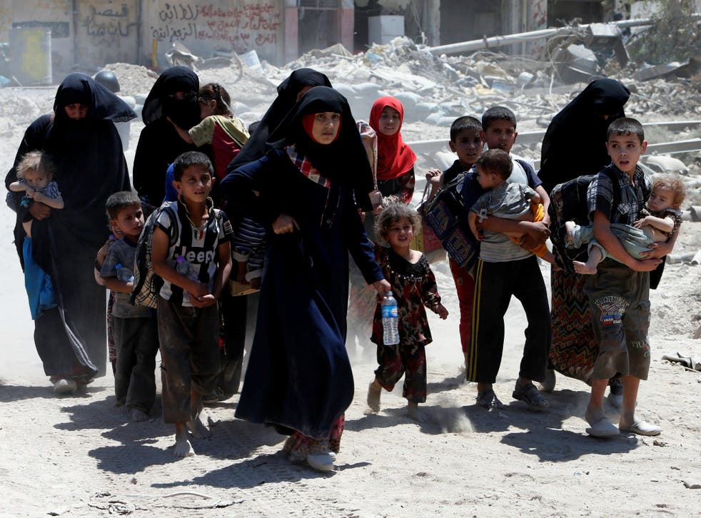 Displaced women and children who fled from clashes walk in the Old City of Mosul