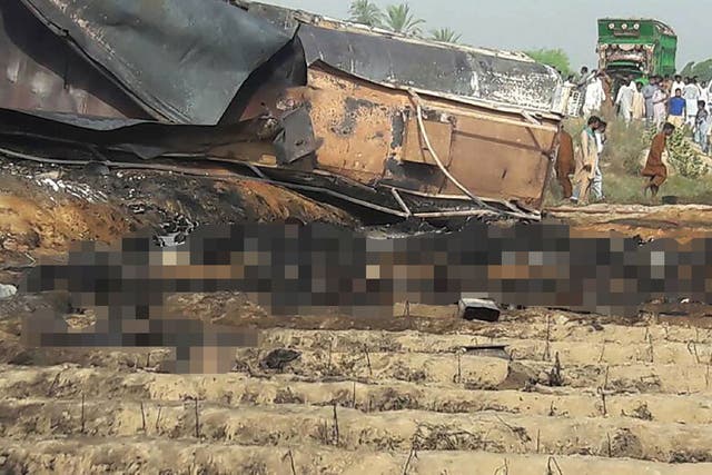 Scores of badly burned bodies (blurred) surround the crashed oil tanker in the aftermath of the horrific blaze