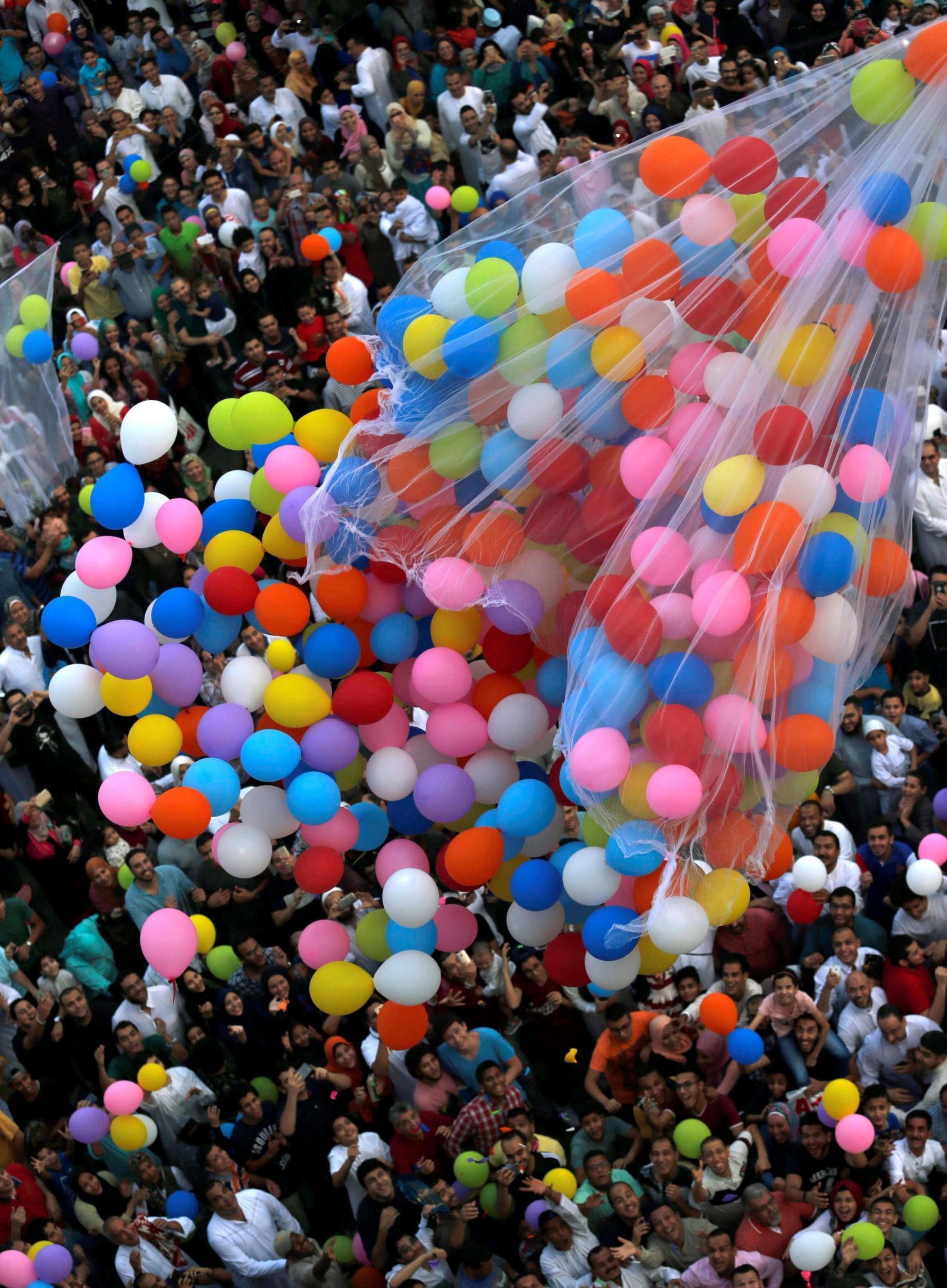 Egyptians try to catch balloons released after prayers, in a public park outside Cairo’s El-Seddik Mosque