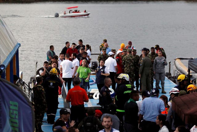 Anxious rescuer workers wait at the dock of the Guatape reservoir as a boat searches for further survivors