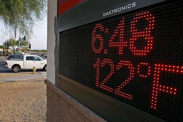 Motorist stop at an intersection where a sign displays the temperature in Phoenix, Arizona