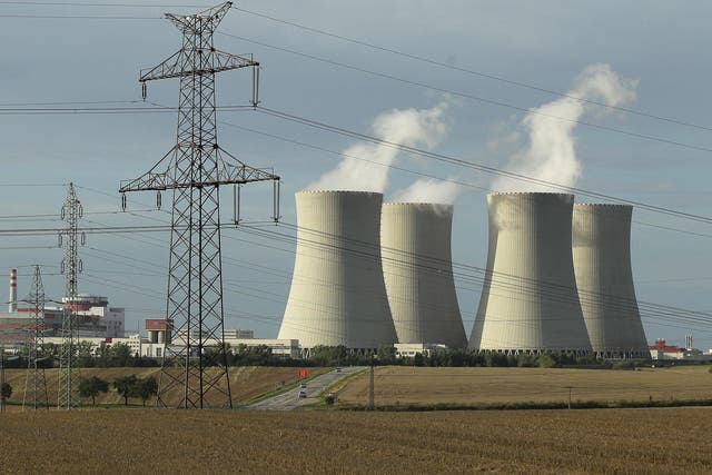 An electricity pylon stands in front of the four cooling towers and two reactor blocks of the Temelin nuclear power plant in