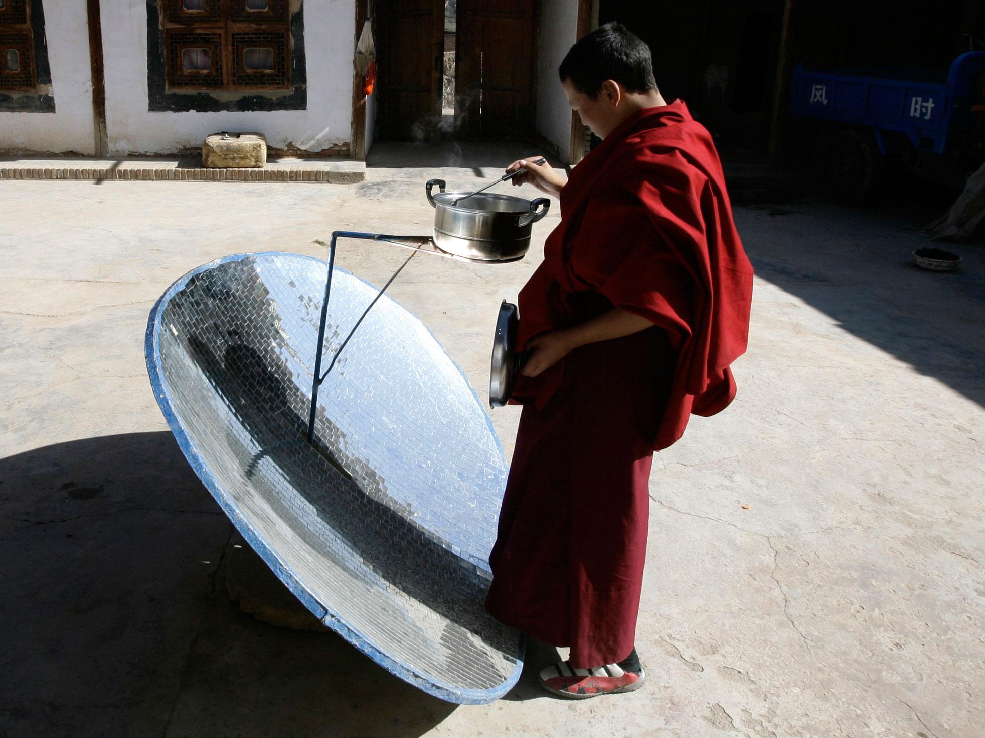 A Buddhist monk makes lunch with a solar stove at Longwu monastery in Tongren, Qinghai