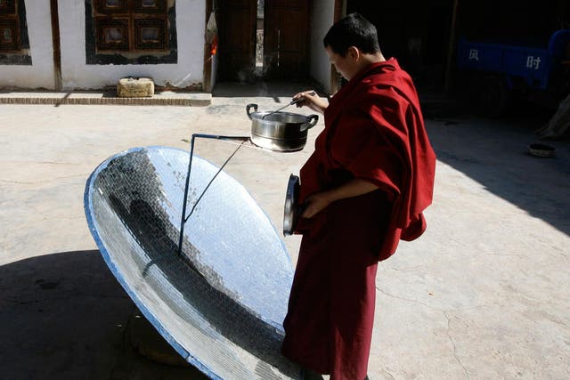 A Buddhist monk makes lunch with a solar stove at Longwu monastery in Tongren, Qinghai