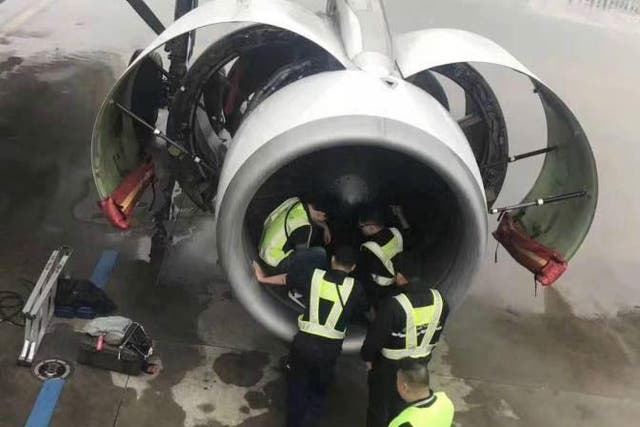 Officials examine the aircraft engine after an elderly woman threw in coins for good luck