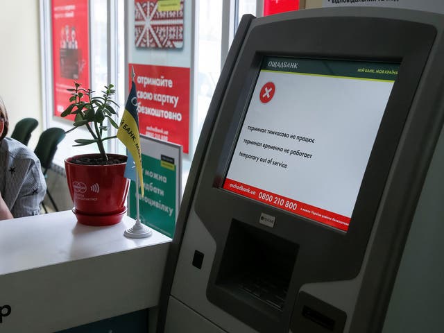 An employee sits next to a payment terminal out of order at a branch of Ukraine's state-owned bank Oschadbank