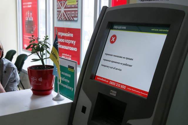 An employee sits next to a payment terminal out of order at a branch of Ukraine's state-owned bank Oschadbank