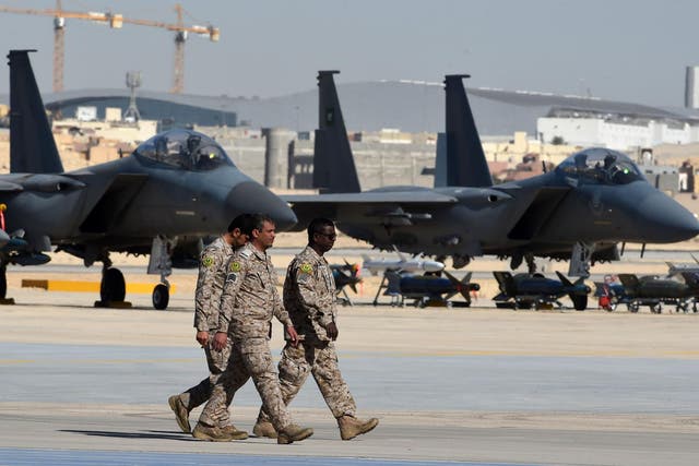 Saudi army officers walk past F-15 fighter jets, GBU bombs and missiles at King Salman airbase in Riyadh
