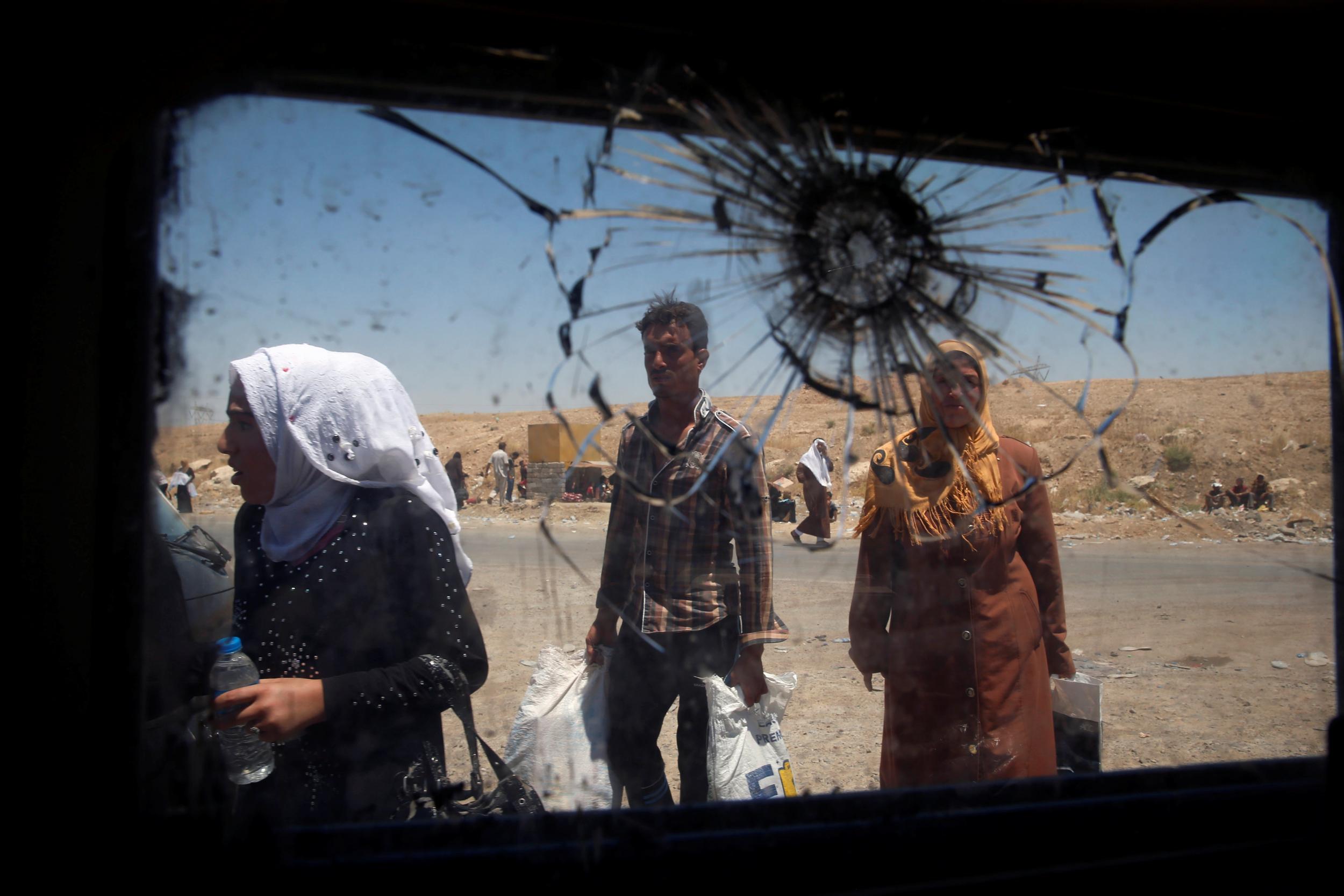 Displaced civilians move past the shattered glass window of an Iraqi forces armoured fighting vehicle in West Mosul, Iraq