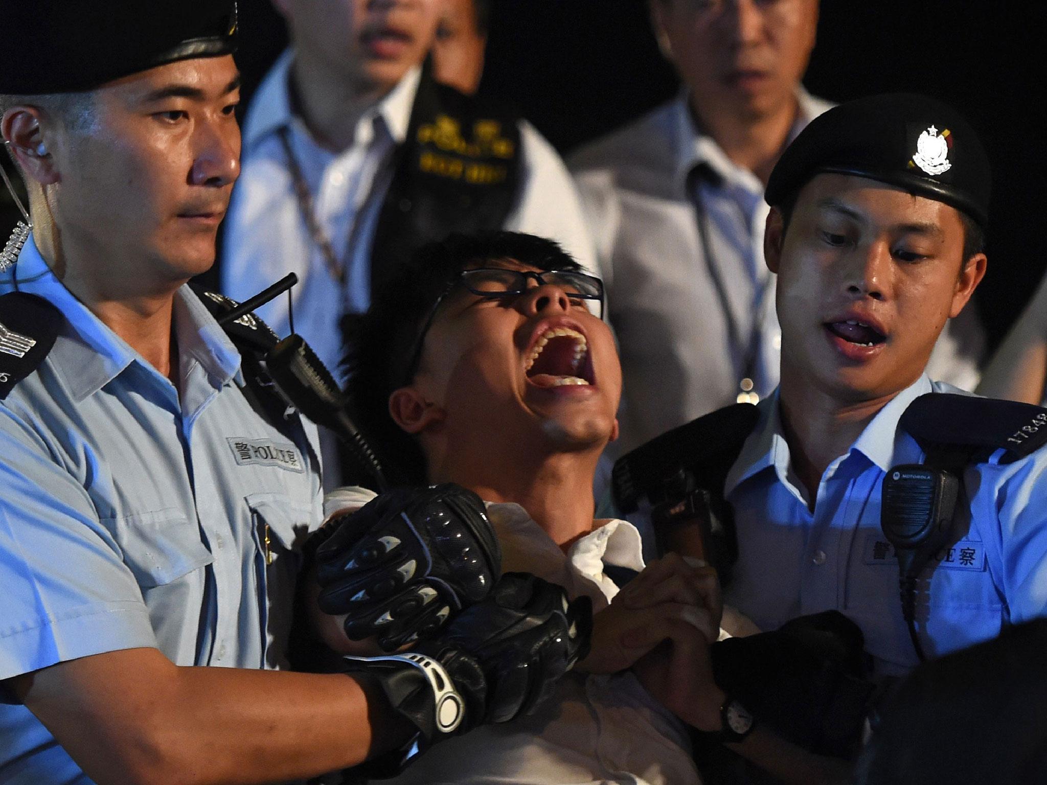 Pro-democracy campaigner Joshua Wong yells as he is taken away by police after he and other demonstrators staged a sit-in protest at the Golden Bauhinia statue, in front of the Convention and Exhibition Centre in Hong Kong