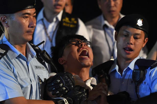 Pro-democracy campaigner Joshua Wong yells as he is taken away by police after he and other demonstrators staged a sit-in protest at the Golden Bauhinia statue, in front of the Convention and Exhibition Centre in Hong Kong